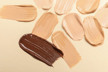 Samples of skin foundation on beige background, closeup