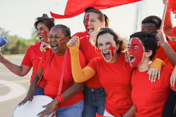 Multi generational people having fun screaming outside of football stadium - Group of red football...