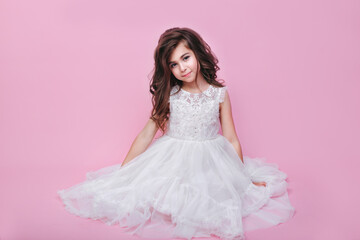 Beautiful little kid girl in white dress sitting on pink background. Happy birthday