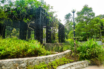 A black pergola surrounded by three levels of green plants 