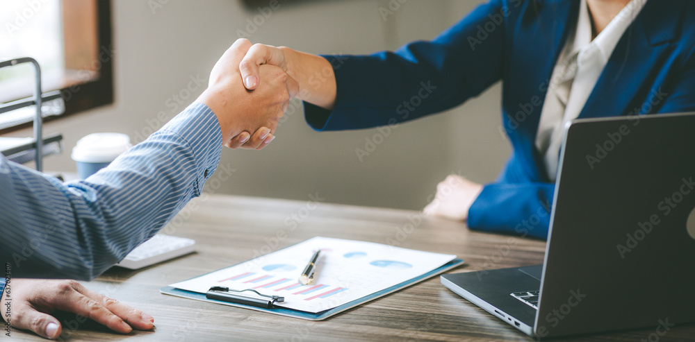 Wall mural Close up of business men and women shaking hands in the workplace team work