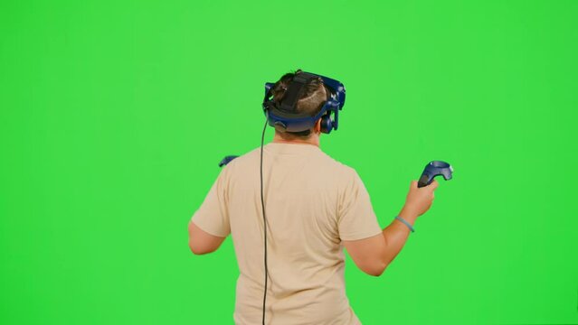 The man on chroma key green screen background in virtual reality dancing in game. The man wearing VR headset dancing in virtual reality. Concept dance in VR headset leisure activity virtual reality
