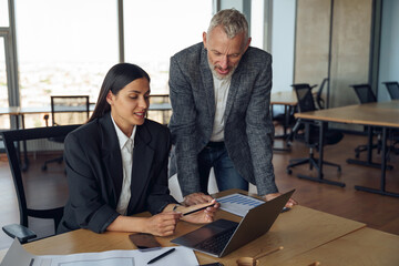 Two colleagues discussing project before showing presentation to team leader in office
