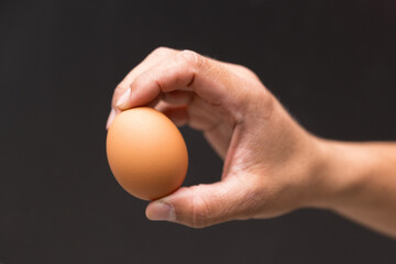 Close up male right hand holding chicken egg for prepare cooking isolate on black background.Hand holding organic produced eggs.
