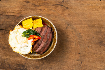 top view Beef Bowl. bowl of white rice topped with slices of grill beef. Japanese food on restaurant table. Isolate on wood background