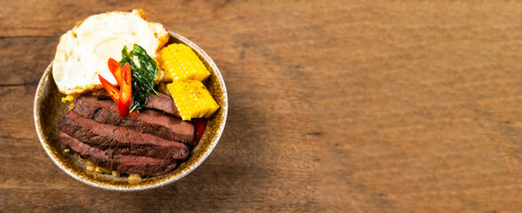 top view Beef Bowl. bowl of white rice topped with slices of grill beef. Japanese food on restaurant table. Isolate on wood background