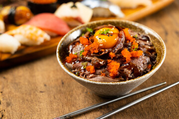 Beef Bowl. bowl of white rice topped with slices of grill beef. Japanese food on restaurant table. Isolate on wood background