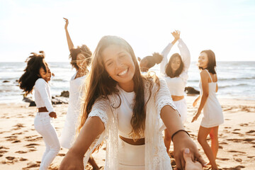 Group of diverse happy ladies having fun and dancing outdoors on the beach, celebrating bachelorette party on coastline