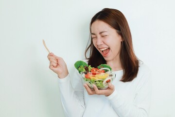 Beautiful Asian woman joyful with salad bowls in her hand, Smiling woman holding organic salad bowl over white background.