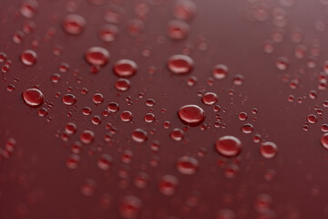 Rain droplets on red sports car surface with hydrophobic treatment