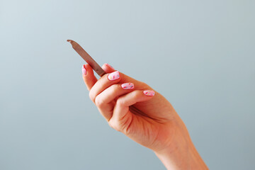 Hand filing nails with glass nail file on the blue background