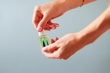 Naklejka premium Female hands with pink manicure hold cosmetic oil on fingers