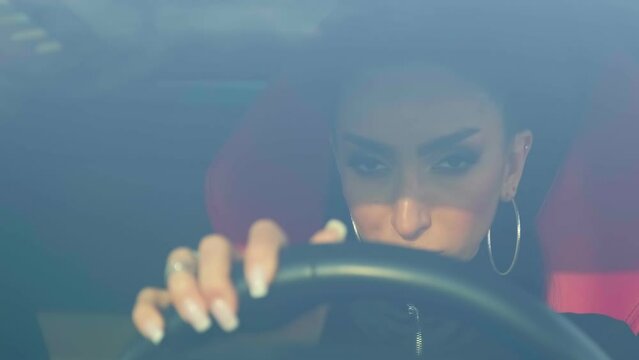 Young brunette in evening makeup and overalls behind the wheel of a premium sports car