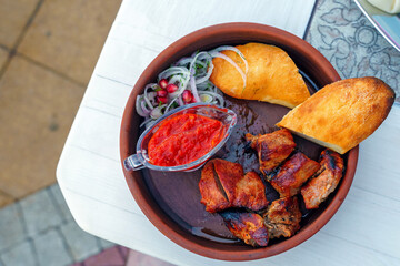 Grilled meat with red tomato sauce and baguette on a plate