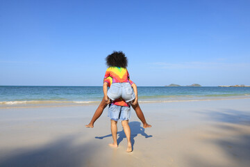 Lesbian woman on back ride with partner laughing in joy and happiness by the beach ,lesbian, and a couple at the beach and piggyback ride for love, summer and vacation together for LGBTQ, travel, and 