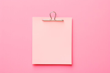 Pink sticky post it note with paper clip on pink background. Mock up of pink note.