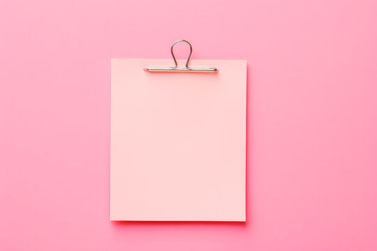 Pink sticky post it note with paper clip on pink background. Mock up of pink note.