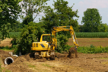 The excavator digs the ground at the construction site for road construction and pipe laying