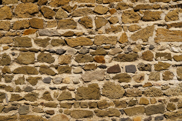 The texture of the old medieval wall of the house, lined with brown stone