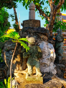 Ancient sculptural image of a cute asian girl in a temple garden in thailand, lingam sculpture.