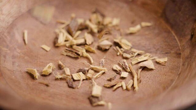 Crushed dried licorice root falling into a wooden dish in slow motion. Herbal detox ingredient. Herbal medicine concept. Glycyrrhiza glabra