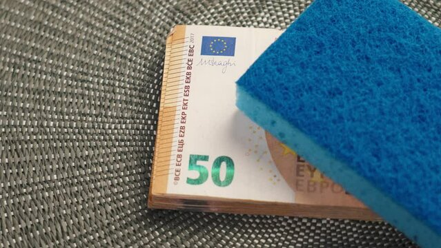 Cleaning sponge on a stack of cash European euro money. Conceptual view of illegal money laundering