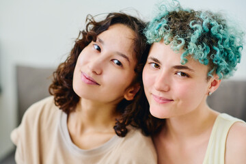 Faces of two happy young intercultural girlfriends in t-shirts looking at camera while standing...