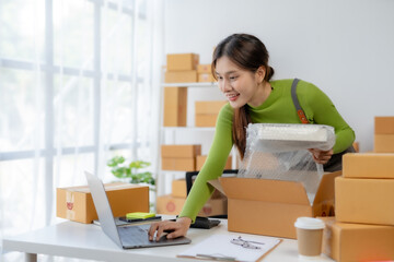 Asian businesswoman starting sme. Owner of a small online business SME Distribution warehouse with boxes SME Online Marketing and product packaging and delivery services.