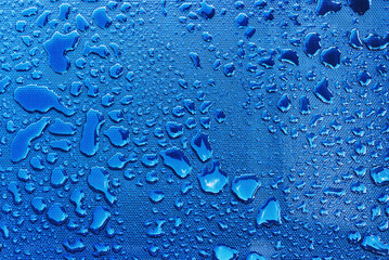 Water drops with light reflection on blue plastic surface as background
