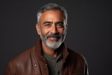 Medium shot portrait of an Indian man in his 50s against an abstract background wearing a chic cardigan