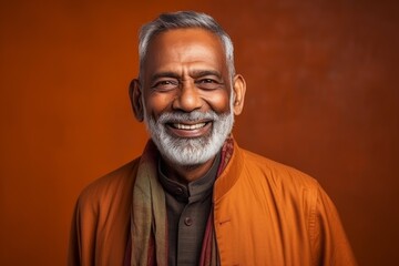 Obraz premium Medium shot portrait of an Indian man in his 60s against an abstract background wearing a chic cardigan