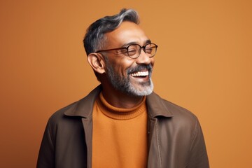 Portrait of a smiling indian man in eyeglasses against brown background