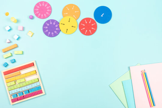 Education, mathematics learning concept. School supplies and colorful math fractions, cubes on light blue background. Top view, copy space
