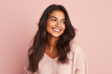 Fototapeta premium Portrait of a beautiful happy young woman smiling against pink background.
