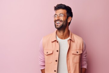 Fototapeta premium Portrait of a handsome young indian man smiling over pink background
