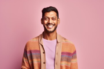 Obraz premium Handsome young indian man smiling and looking at camera while standing against pink background
