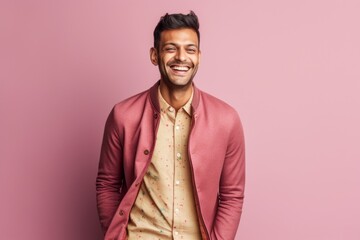 Fototapeta premium Portrait of a happy young indian man smiling against pink background
