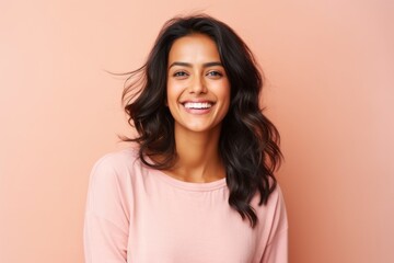 Obraz premium Portrait of a beautiful young woman smiling at the camera over pink background