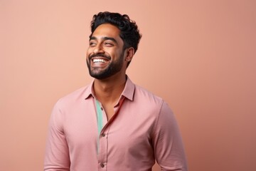 Obraz premium Portrait of a young indian man laughing against pink background.