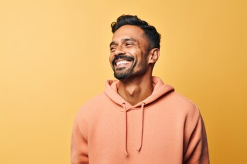 Fototapeta premium Portrait of a happy indian man laughing on a yellow background