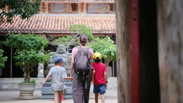Mother with 5 year old and 7 year old son exploring temple in Vietnam caves statues Buddhism family adventure single parent mother and adventurous children Southeast Asia