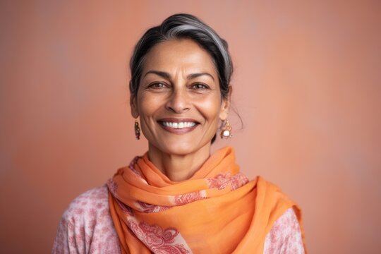 Portrait of a smiling middle-aged Indian woman wearing an orange scarf