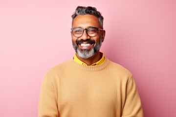 Obraz premium Portrait of a happy Indian man in glasses and a yellow sweater against a pink background