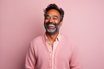 Obraz premium Portrait of happy indian man laughing with closed eyes on pink background