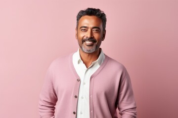 Obraz premium Portrait of a smiling Indian man looking at camera while standing against pink background