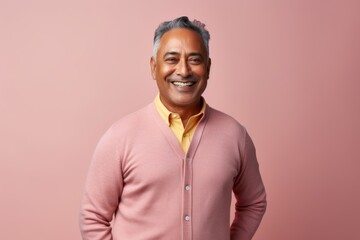 Obraz premium Portrait of happy mature indian man standing on pink background.