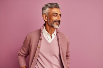 Obraz premium Portrait of mature Indian man looking at camera while standing against pink background