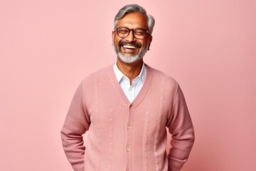 Portrait of a smiling Indian man in glasses standing against pink background