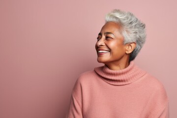 Smiling african american woman in pink sweater against pink background