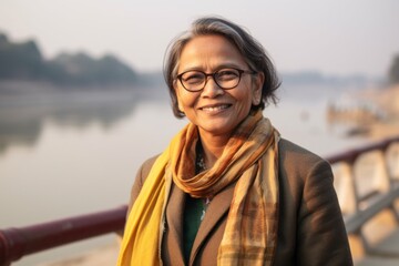 Close-up portrait of an Indian woman in her 50s wearing a classic blazer at the banks of the Ganges river